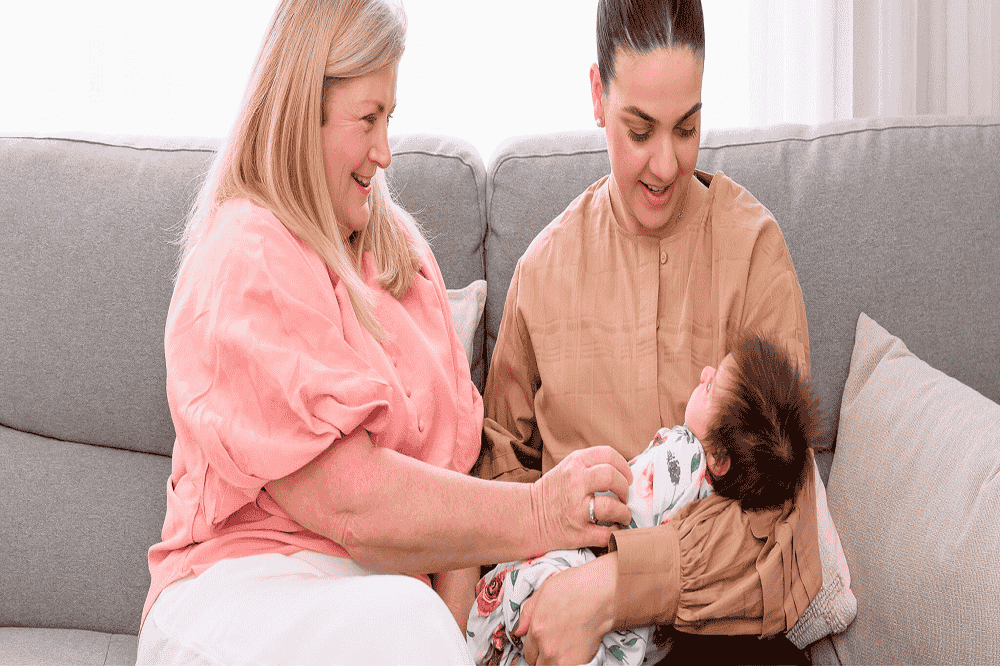 Two women smiling with newborn baby